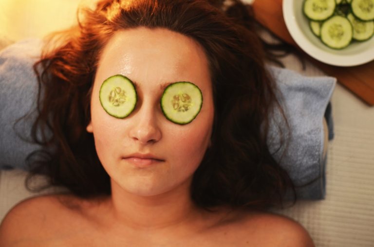 Women laying down with cucumber slices on her eyes